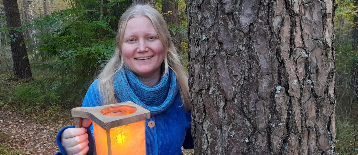 Berätterskan Stina Gray med en lykta i skogen på hösten.