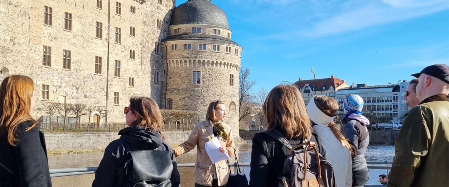 En grupp människor står framför en guide och Örebro slott.